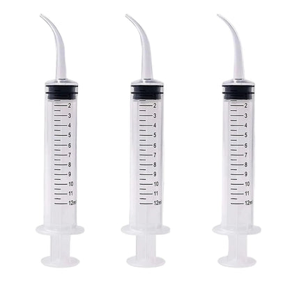Three plastic syringes with measurement markings on a gray background